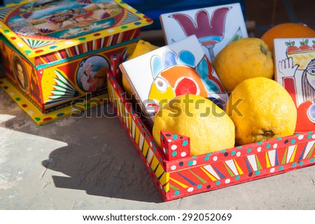 Typical colored wooden little box with lemons and painted ceramic tiles on the external window sill of a stone house in the fishing village Marzamemi