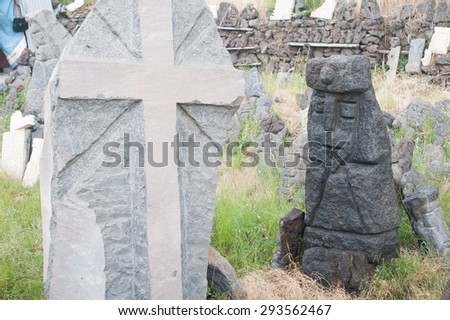 Gray lava stone sculpture of a christian cross and a lava half-length of an old sovereign poured with water