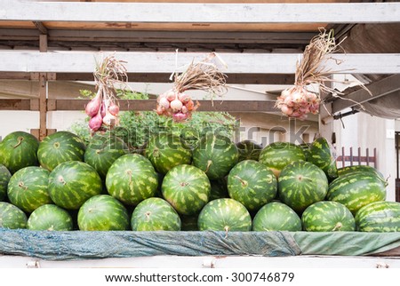 Watermelons and onions arranged for sale on the truck of a street seller