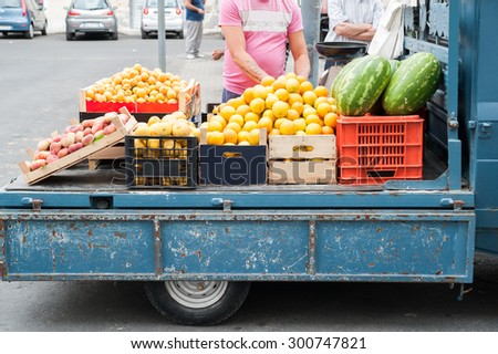 A characteristic Ape car of a street fruit seller full of wooden fruit boxes in a street of Sicily