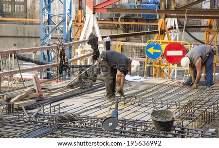 Barcelona, Spain - March 7, 2014: Construction workers are doing a floor for a luxury hotel in the old town. Construction workers are doing a floor with two road signs behind.