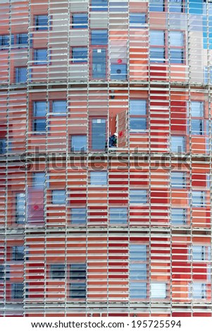Barcelona, Spain - March 12, 2014: A cleaner in action in the Agbar building in Barcelona. A cleaner in action at Barcelona Agbar building which stands out for its red color.