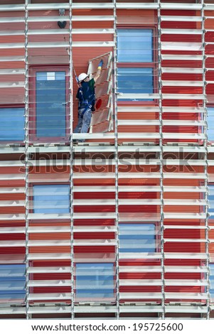 Barcelona, Spain - March 12, 2014: A cleaner in action in the Agbar building in Barcelona. A cleaner in action at Barcelona Agbar building which stands out for its red color.