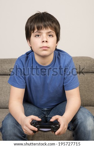 Video gamer boy. Young boy 10 years playing videogame sitting on sofa with watchful eyes