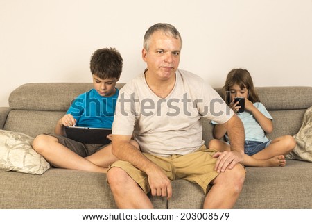 children sitting on the sofa playing while his father does not know what to do