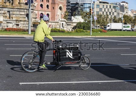 Barcelona, Spain - November 7, 2014: An interesting bike with a cargo box running through a square in Barcelona