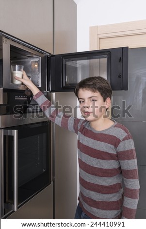 Young boy warming a glass of milk in the microwave
