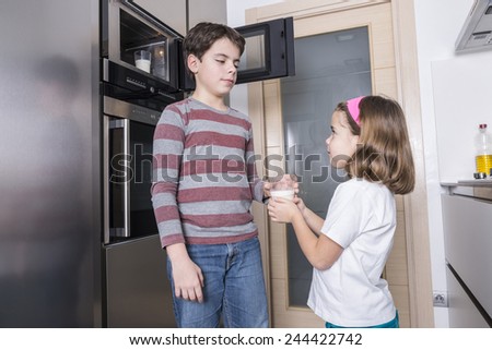 Children warming a glass of milk in the microwave