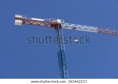 Construction crane blue, white and red against clear blue sky