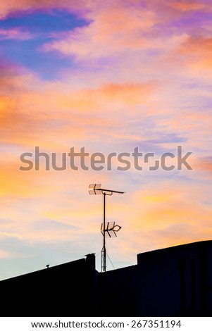 Silhouettes of antennas backlit at sunset with colorful sky clouds