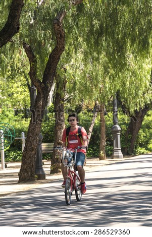 Barcelona, Spain - April 14, 2015: Cyclist circulating and listening to music by a bike path in central Barcelona