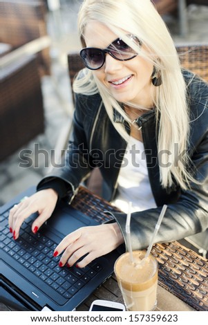 Young girl typing on lap top in cafe