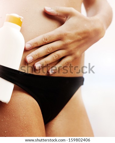 Suntan lotion and female body in swimming suit