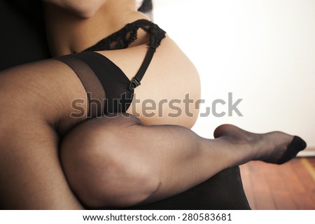 Female body detail, legs and foot in nylon stockings and garter belt