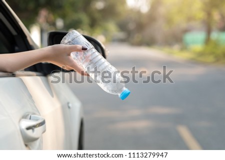Hand throwing plastic bottle on the road