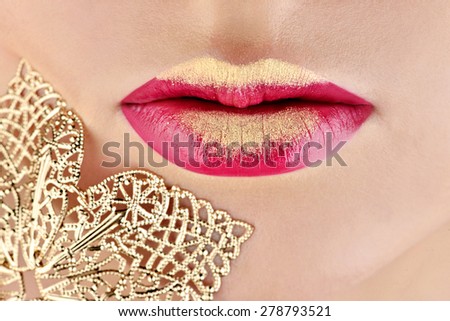 Jewelry near painted golden lips. Portrait of sexy fashion model girl with perfect bright makeup. Beautiful woman with red glossy lips. Close-up of burgundy lips. Shiny face of a young white girl