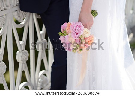 Female and male portrait with bouquet. Wedding couple. Beautiful sexy model girl in white dress. Man in suit. Beauty bride with groom. Woman in bridal gown. Cute lady and guy outdoors
