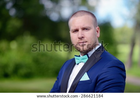 Beauty groom in suit on the nature. Male portrait in the park. Beautiful model boy in colorful wedding clothes. Man is posing. Handsome guy outdoors