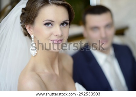 Wedding couple indoors is hugging each other. Beautiful model girl in white dress. Man in suit. Beauty bride with groom. Female and male portrait. Woman with lace veil. Cute lady and handsome guy