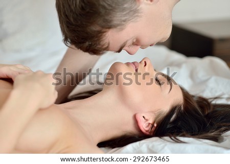 Young sexy couple on the bed. Beautiful lady and guy in erotic pose. Portrait of girl and boy indoors. Cute woman and handsome man are hugging each other. Beauty naked models