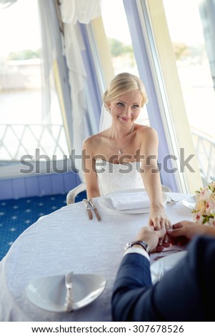 Wedding couple is holding hands. Beauty bride with groom. Beautiful model girl in white dress. Man in suit. Female and male portrait. Woman with lace veil. Cute lady and guy indoors