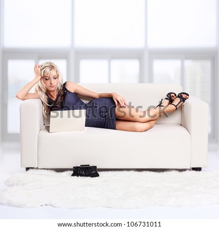 full-length portrait of beautiful young blond woman relaxing on couch with laptop