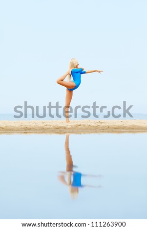 outdoor portrait of young beautiful blonde woman gymnast working out on the beach