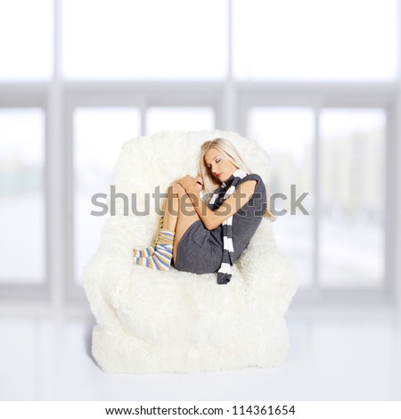 portrait of beautiful blonde sitting on big white furry arm-chair