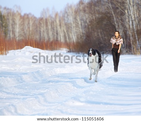 outdoor portrait of beautiful brunette woman with running russian wolfhound in snowy winter forest