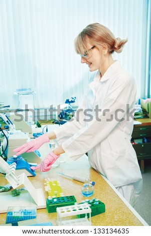 portrait of happy young woman scientist working in laboratory with equipment in protective gloves