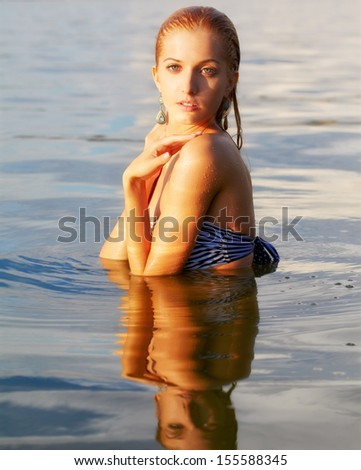 outdoor portrait of young beautiful tanned blonde woman in ocean waters
