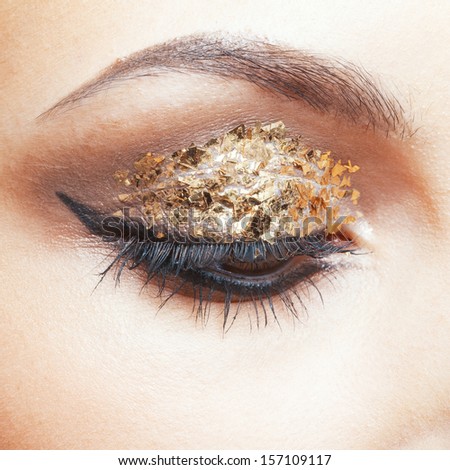 Close-up shot of female face with vogue golden shining eye makeup