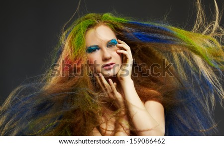 portrait of young beautiful red-haired woman with long curly hair colored with green red and blue