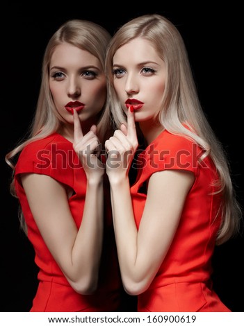 portrait of young beautiful blonde woman in red dress at mirror asking to be quiet