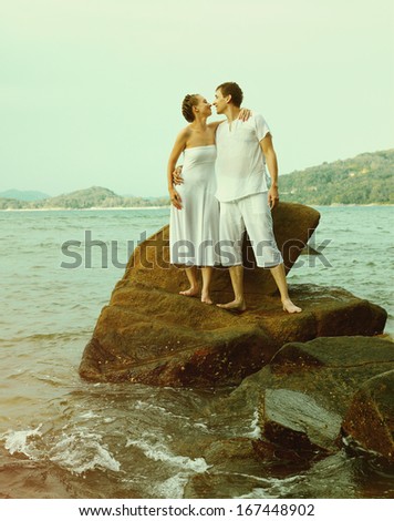 Colorized vintage outdoor portrait of young romantic couple in white cotton clothes on beach of Phuket island, Thailand