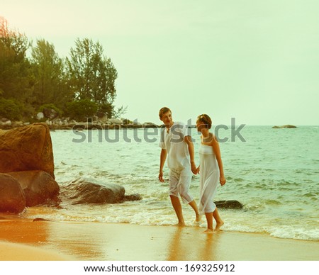 Old film retro colorized vintage outdoor portrait of young romantic couple in white cotton clothes on beach of Phuket island, Thailand