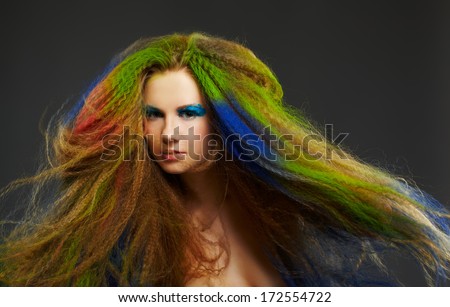 portrait of young beautiful red-haired woman with waving hair colored with green red and blue