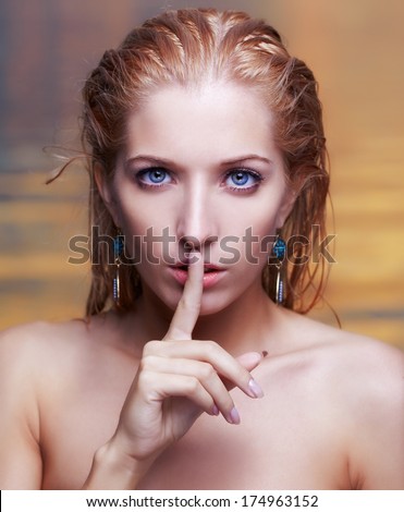 portrait of young beautiful blonde woman asking to be quiet. sea waters on background.