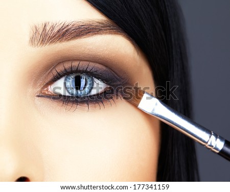 Close-up shot of woman face and makeup brush  applying mascara make-up on eye lashes