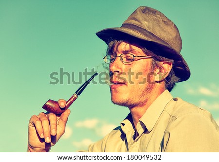 Colorized vintage outdoor portrait of man in hat smoking tobacco-pipe