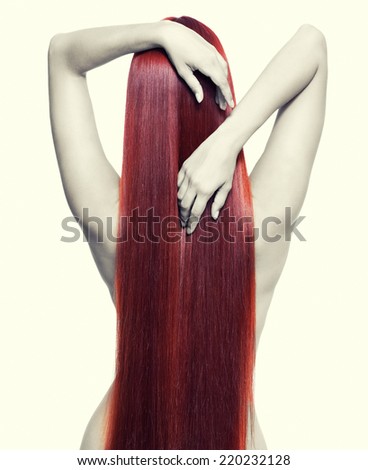 Portrait of beautiful young nude woman with long red hair. View from back side