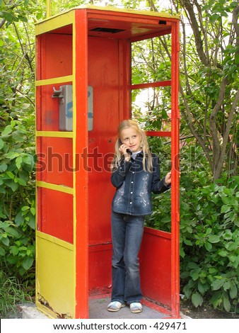 Little girl in the old public call-box with mobile phone - slight blur