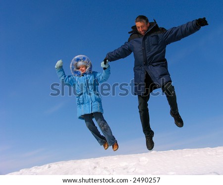 Happy family jumping over snow under blue sky