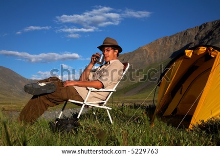 man is sitting in the chair at the camp in mountains