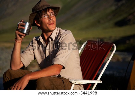 man is sitting in the chair with a pot outdoors