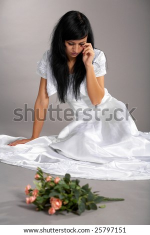 pretty bride sits on the floor and cries with flowers thrown nearby