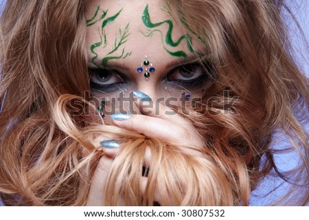 portrait of beautiful girl with bodyart of algae posing on blue and hiding her face in hair
