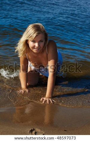 beautiful blonde girl posing in wet peignoir in the waters of sea