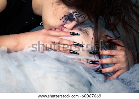 portrait of girl with spider bodyart of face zone and her victim boy in cocoon