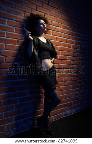 portrait of girl dressed like hooker posing near brick wall